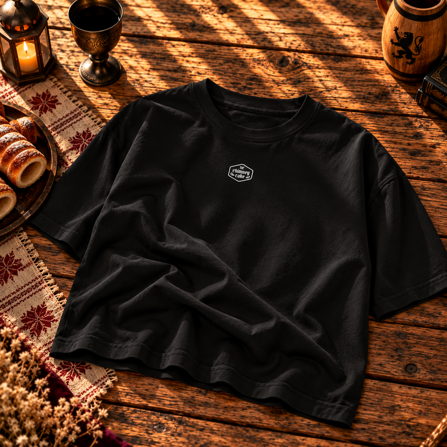 Black boxy tee laid flat with a small Chimney Cake crest on the chest
