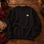 Front of the black sweatshirt with a small Chimney Cake badge on the left chest, beside chimney cakes and cinnamon sticks