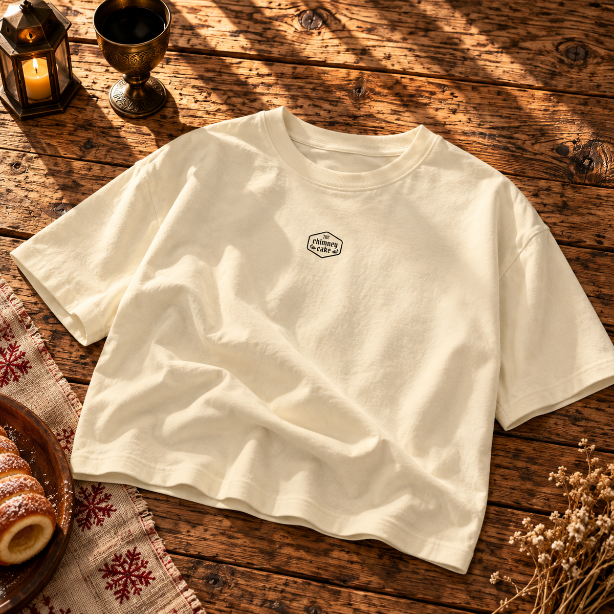 Creme boxy tee laid flat with a small Chimney Cake crest on the chest